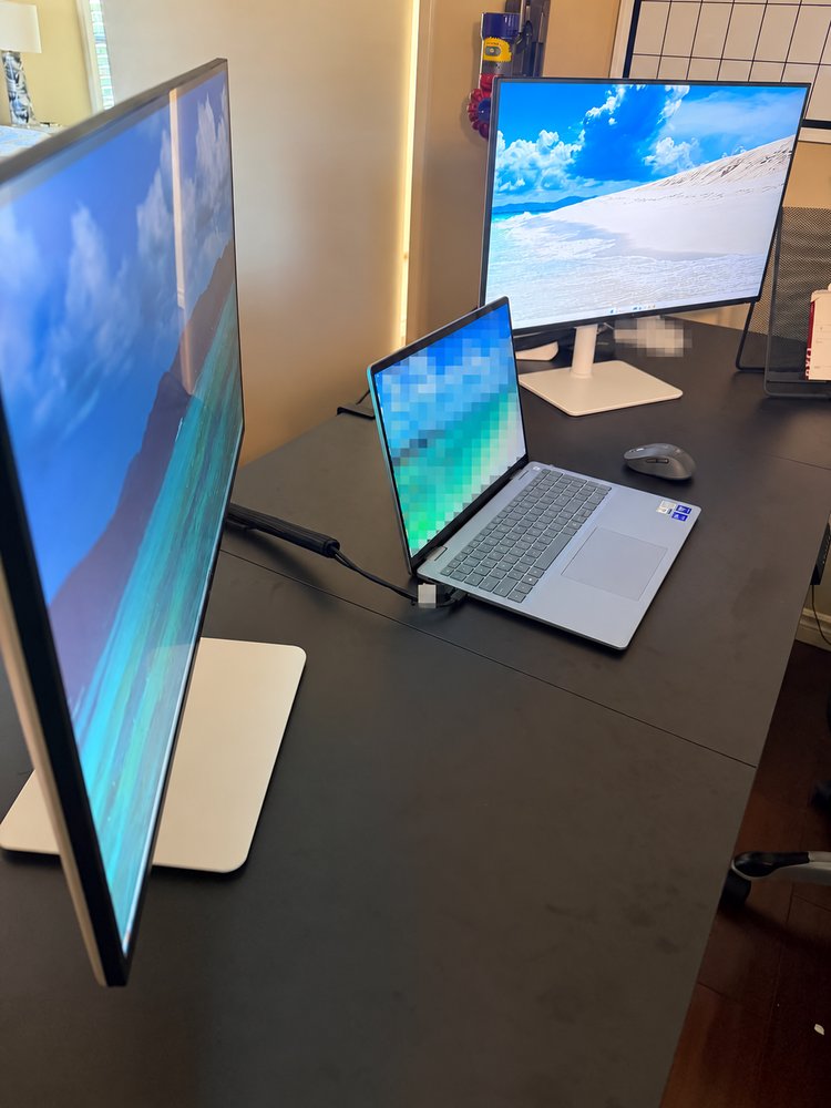 A laptop connected to two external displays on a home-office desk